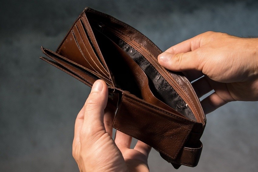 Hands holding brown leather wallet, stretched opened to show lack of cash or credit cards inside