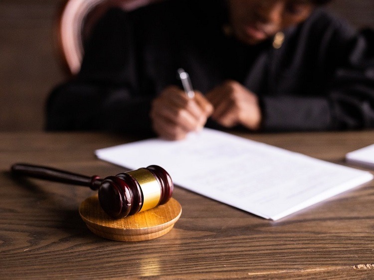 Judge in black robe signing legislation at desk with wooden gavel